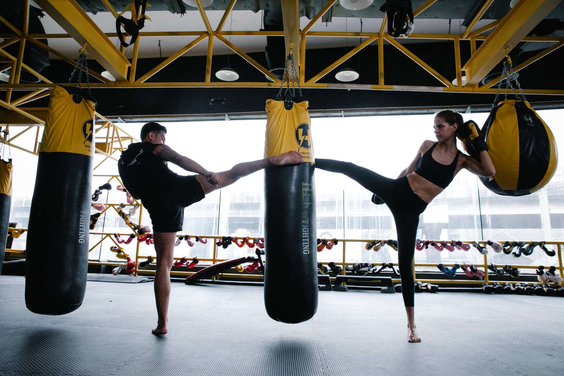 a man and woman kicking a punching bag together
