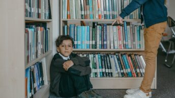 a person finger pointing to a boy sitting on the floor