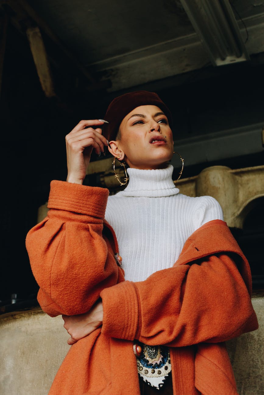 low angle photo of woman in white turtleneck and orange coat posing