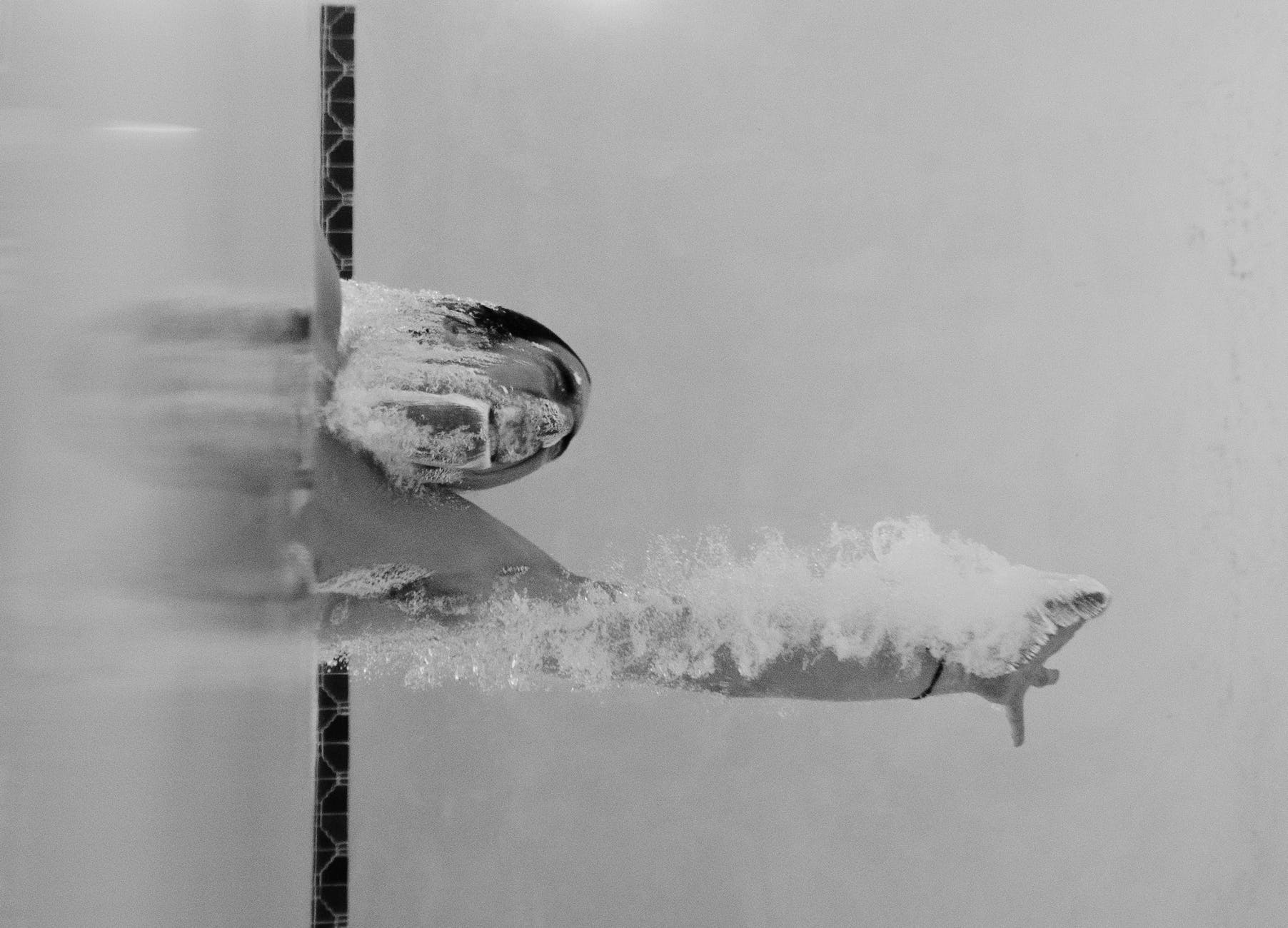 person swimming at the pool in grayscale photo